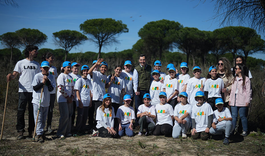 Foto de familia de Juanma Moreno con los j&oacute;venes que participan en una plantaci&oacute;n de &aacute;rboles en el paraje de 'Las Pe&ntilde;uelas', dentro del Espacio Natural de Do&ntilde;ana.
