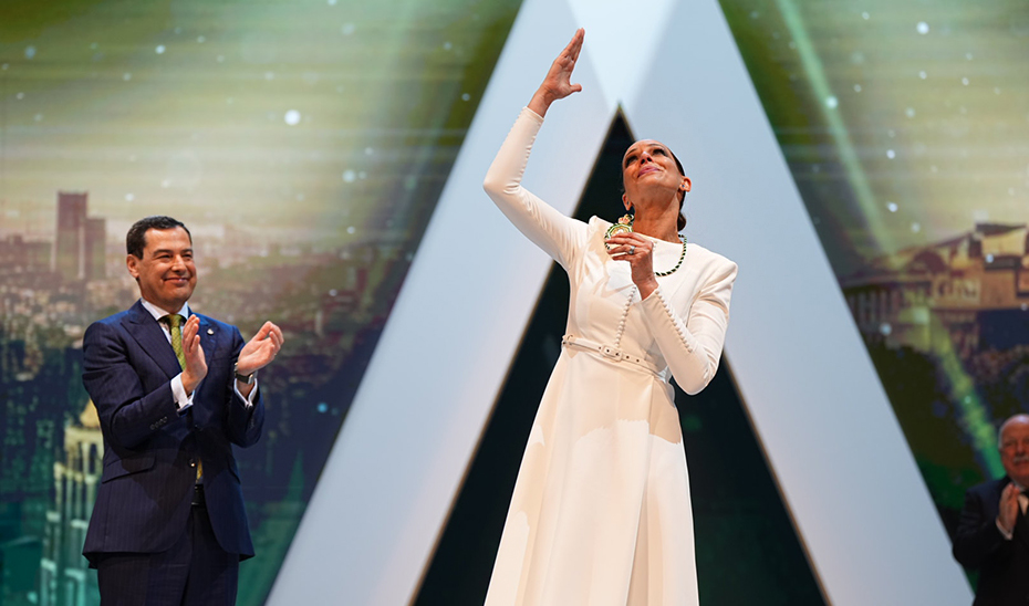 La modelo y presentadora de televisi&oacute;n Eva Gonz&aacute;lez brinda al cielo la Medalla de Andaluc&iacute;a ante el aplauso de Juanma Moreno.